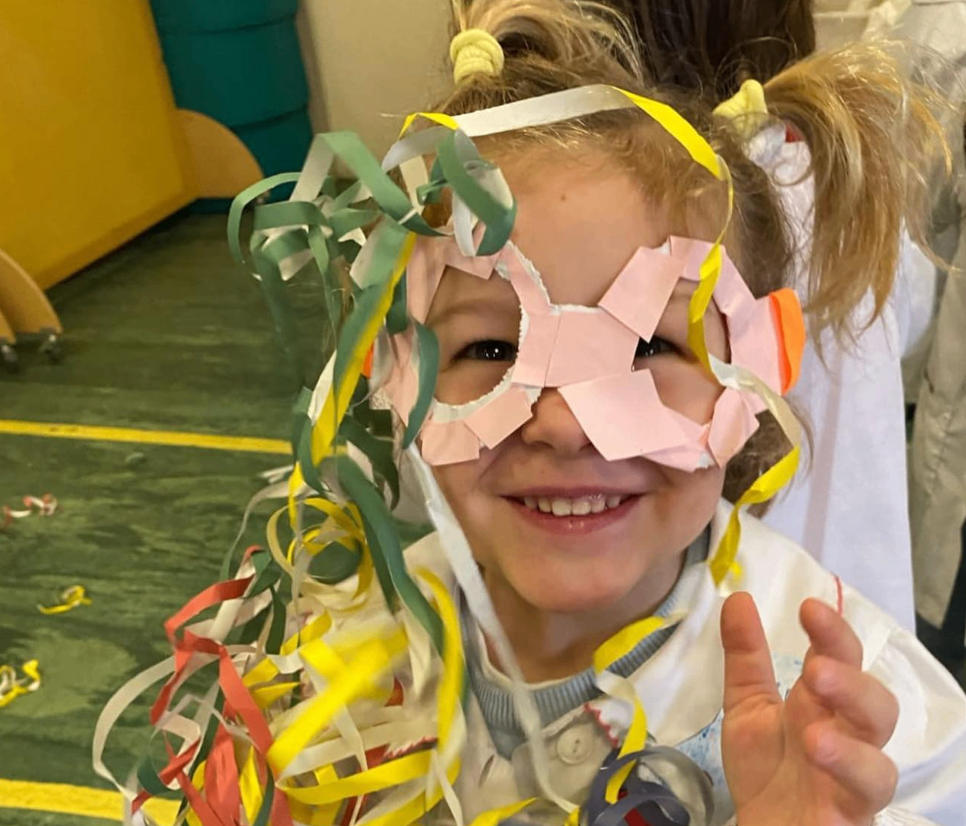 Bambina sorridente con una maschera di carta realizzata durante un'attività di gioco creativo